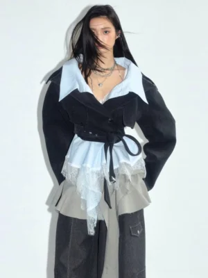Close-up of women's dark gray deconstructed cropped blazer with light blue contrast shirt collar lace hem and elongated waist belt detail