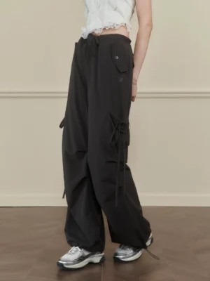 Women's dark gray side-tie wide-leg cargo pants shown from a low rear three-quarter view in a streetwear studio outfit