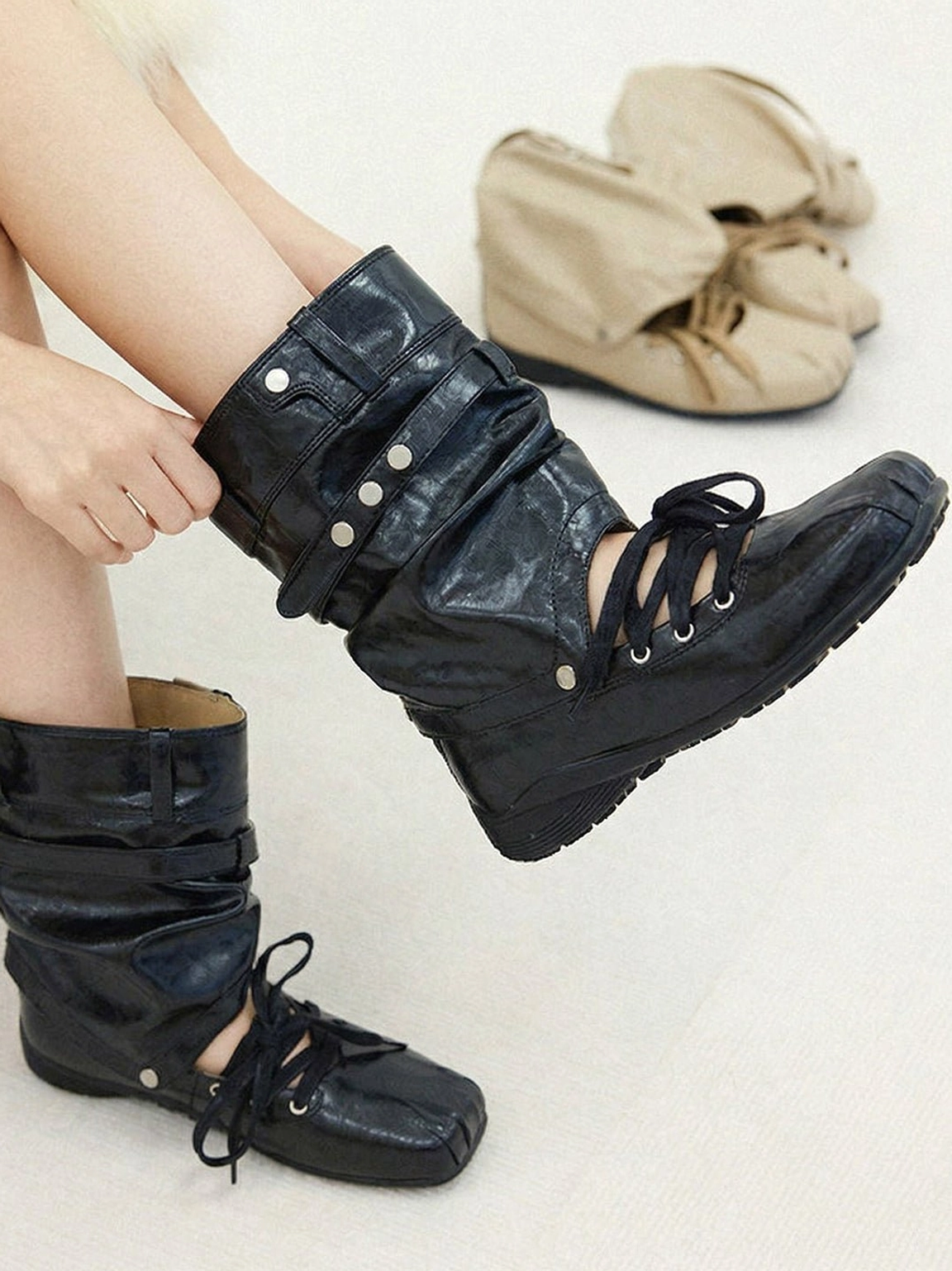 Women's black detachable bow cutout utility boot being put on, showing square toe and metal strap details