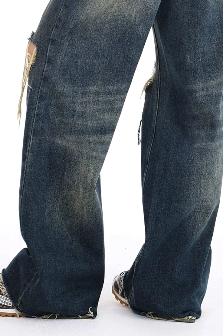 Distressed dark wash wide leg ripped jeans styled as contemporary women's streetwear with a high-rise waist, relaxed leg shape, vintage blue denim, and frayed detailing