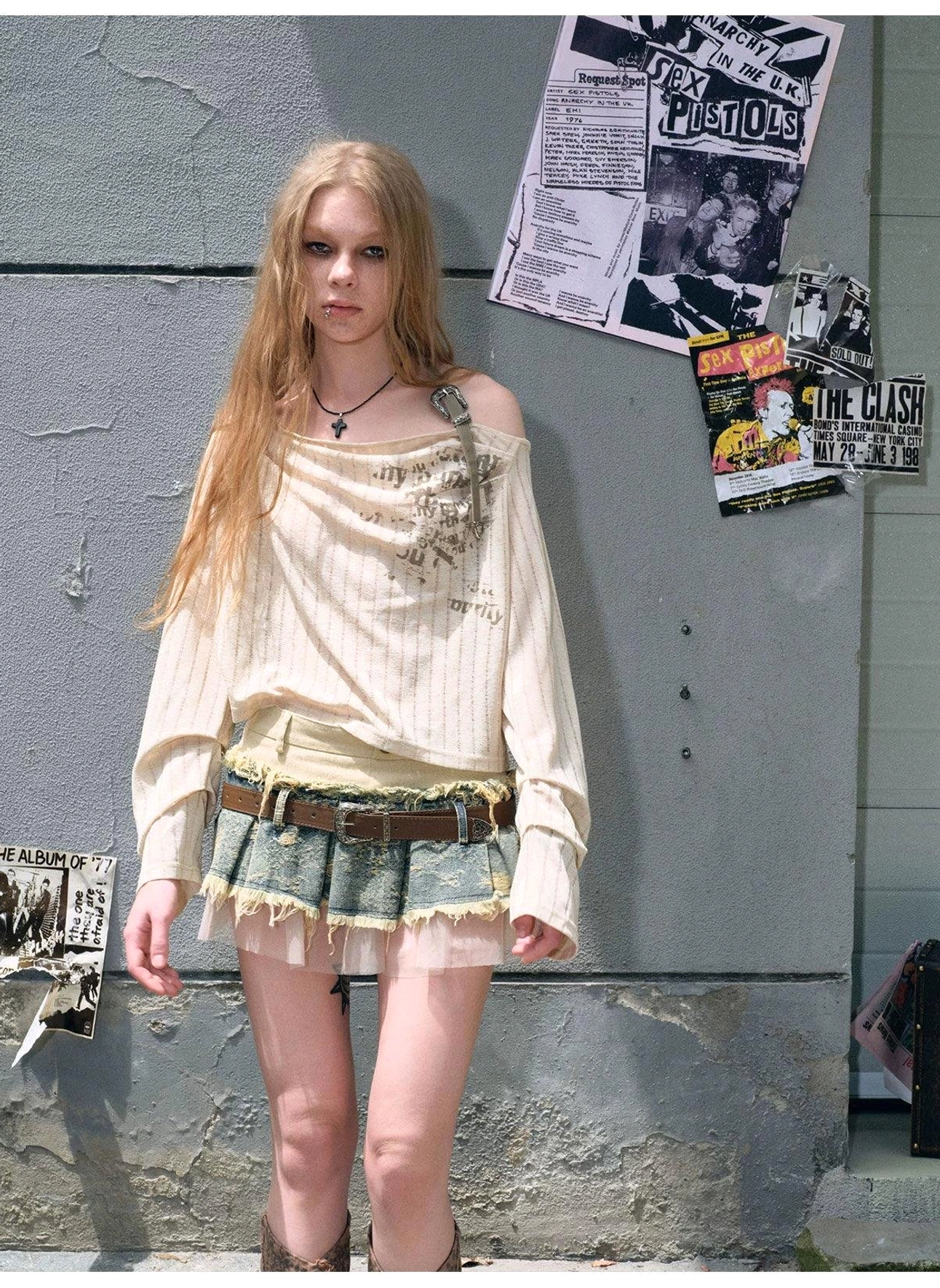 Women's distressed denim mini skirt featuring a sheer tulle underlayer, frayed raw hem, vintage belt, and Acubi streetwear aesthetic