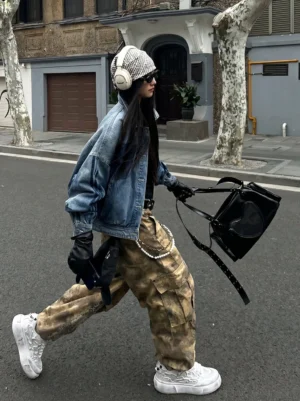 Female model wearing distressed white panda platform sneakers with denim jacket and camo cargo pants on an urban street
