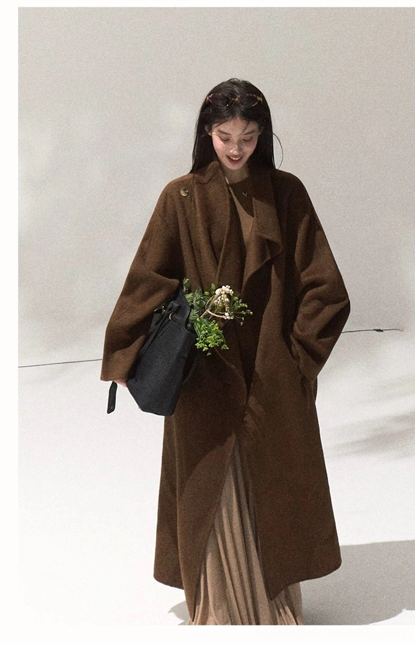 Women's camel brown draped longline wool overcoat layered over a flowing maxi skirt in minimalist streetwear styling