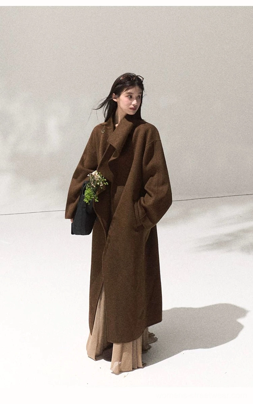 Side three quarter view of women's camel oversized draped wool overcoat with long relaxed silhouette