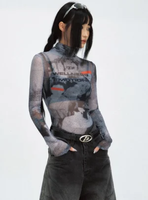 Side view of a women's fitted sheer mesh long-sleeve turtleneck top styled with black wide-leg denim and a silver belt