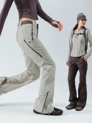 Women's flared outdoor performance pants shown in light gray and dark brown color options with zipper pockets, elastic waistband, and ankle details