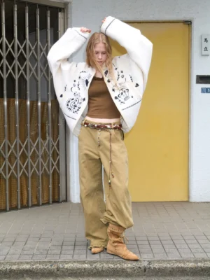 Women's folk tale embroidered cropped sherpa jacket styled with brown crop top khaki wide-leg pants and boots outdoors