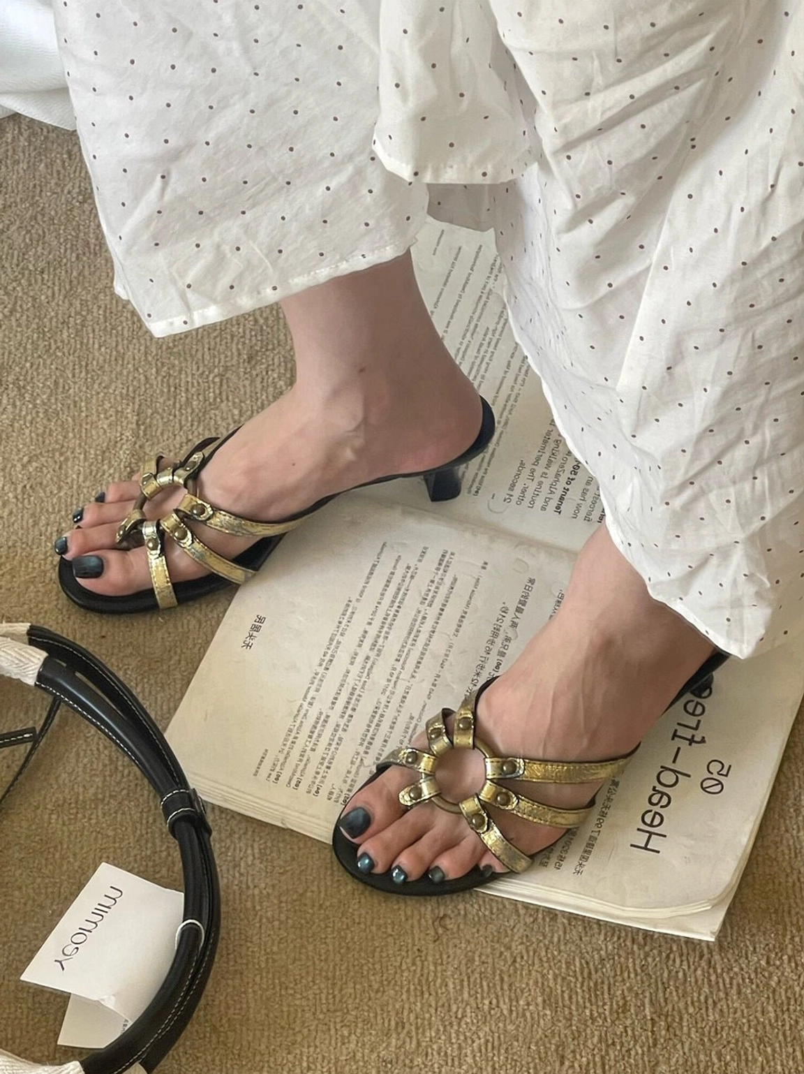 Angled view of women's gold metallic sandals with textured straps, low kitten heels, open toes, and polished fashion styling