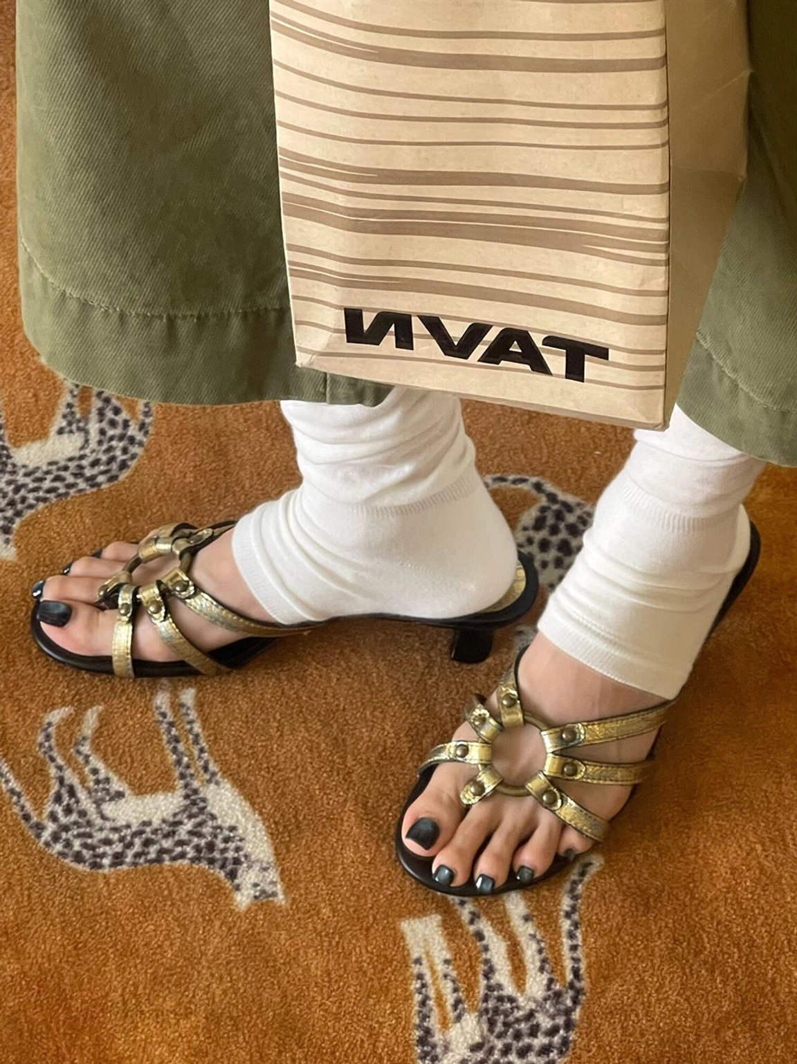 Side view of women's gold strappy kitten-heel sandals with matching metallic hardware and black low heels
