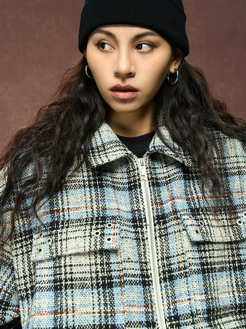 Female model wearing a neutral gray plaid oversized shirt jacket with front zipper and dual utility chest pockets