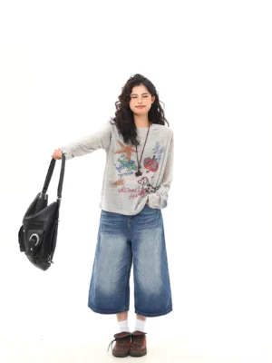 Women's heather gray graffiti print long sleeve tee styled with black shoulder bag and wide leg denim
