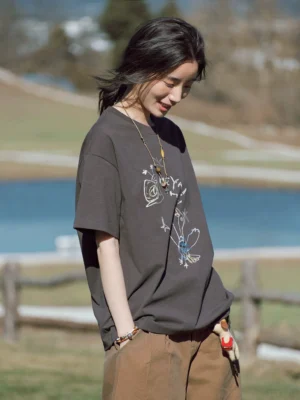 Women's charcoal gray HEYA HO bird sketch oversized graphic T-shirt side view with khaki cargo pants