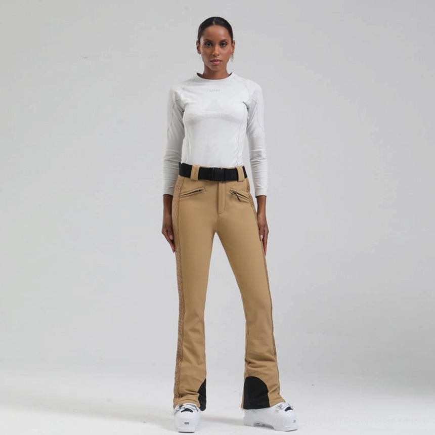 Khaki women's flared snow pants with black heel guards, front zip pockets, quilted side panels, and adjustable ski belt
