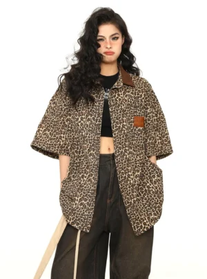 Women's leopard print oversized short-sleeve workwear shirt styled open over a black crop top with dark wide-leg jeans