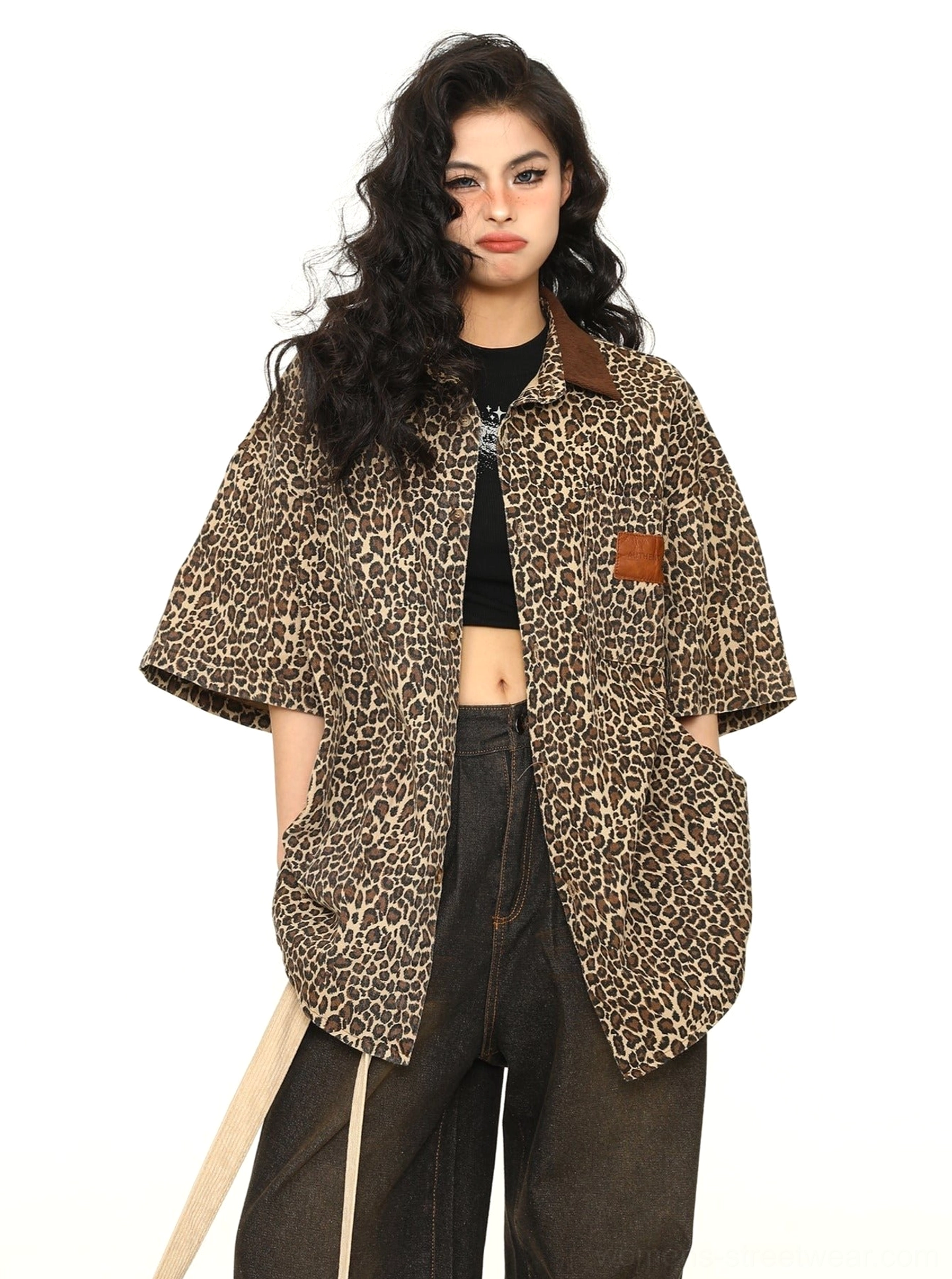 Women's leopard print oversized short-sleeve workwear shirt styled open over a black crop top with dark wide-leg jeans