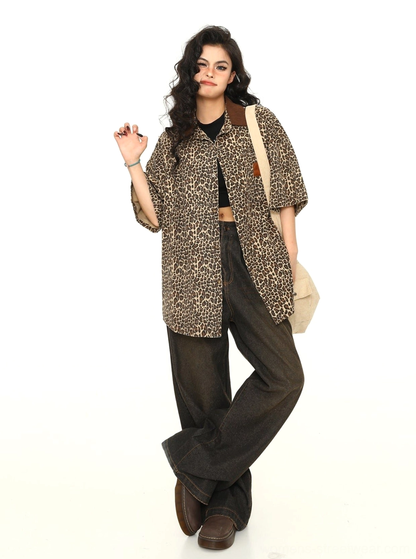 Three-quarter front view of women's leopard print oversized workwear button-up shirt styled with a crossbody bag and dark trousers