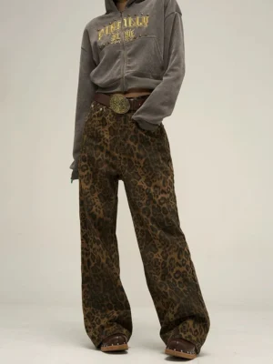 Front view of women's brown and black leopard print wide leg streetwear pants styled with a grey zip-up hoodie, brown belt, and leather clogs