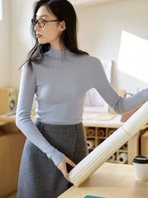 Soft light blue slim fit mock neck knit sweater styled with a gray midi wrap skirt in a modern office outfit
