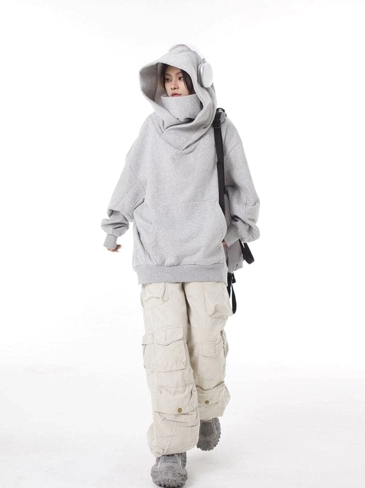 Women's light gray oversized hooded pullover with built-in high neck, relaxed silhouette, cargo pants, and casual streetwear sneakers