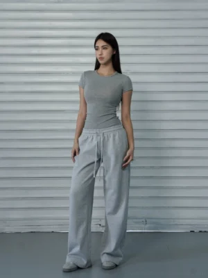 Women's light gray slim-fit crew-neck short-sleeve streetwear T-shirt styled with wide-leg sweatpants in a full-body front view