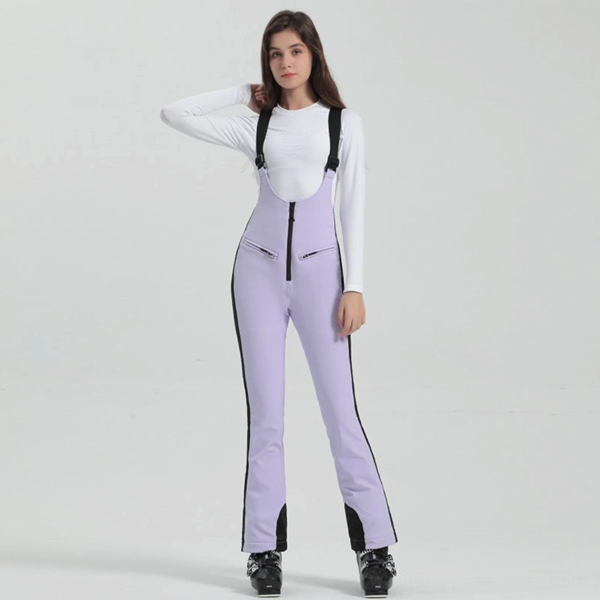 Women's light lilac purple bib ski overalls with black side stripes, adjustable suspenders, front zipper, flared legs, and ski footwear