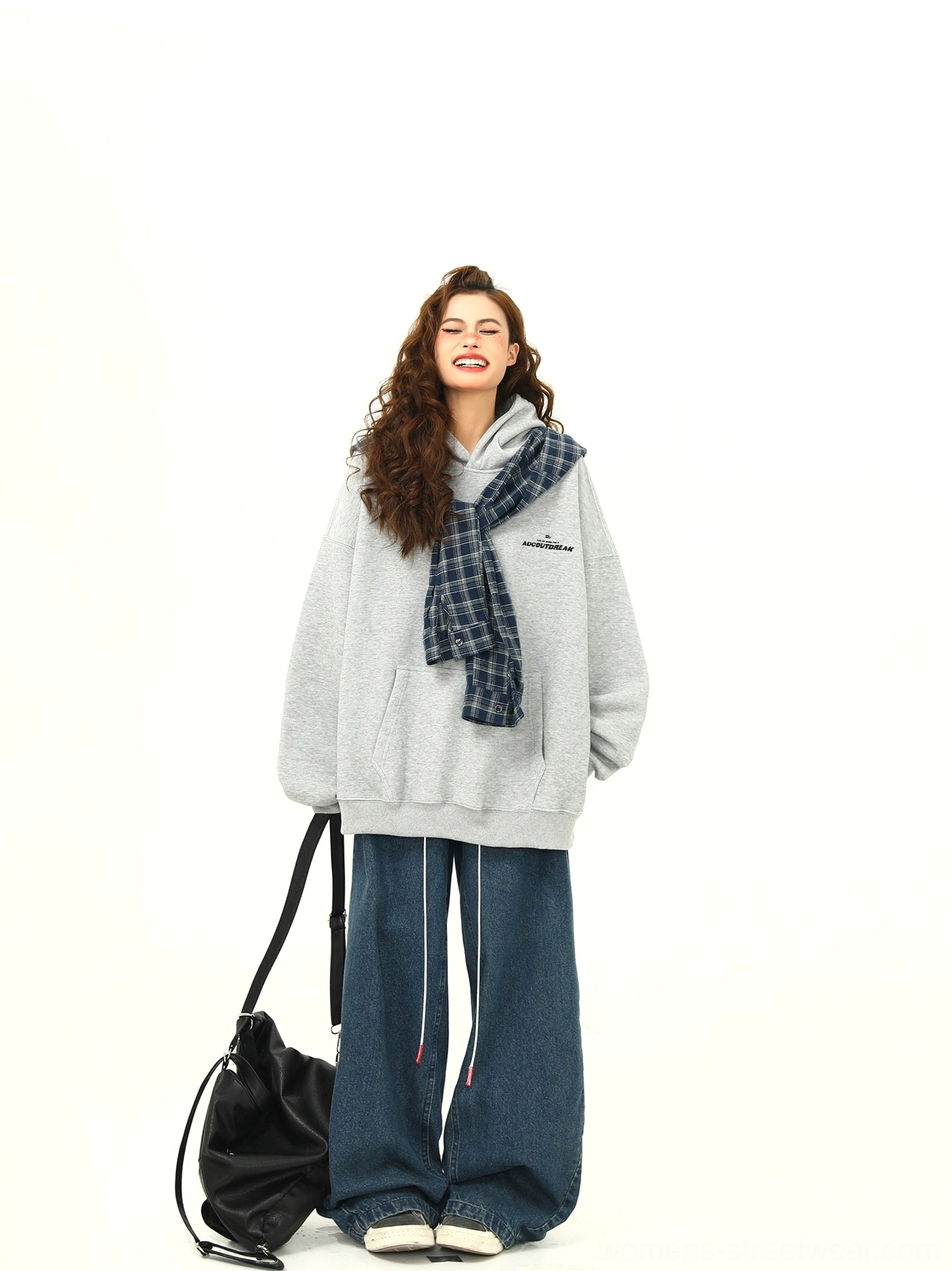 Front medium view of a loose fit women’s heather grey plaid accent hoodie with blue plaid hood detail and black handbag for everyday streetwear styling