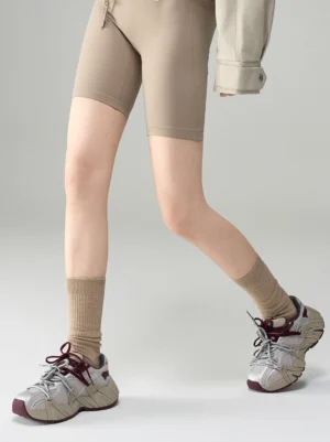 Women's beige mesh cage runner sneakers styled with tan crew socks and biker shorts for a Seoul streetwear outfit