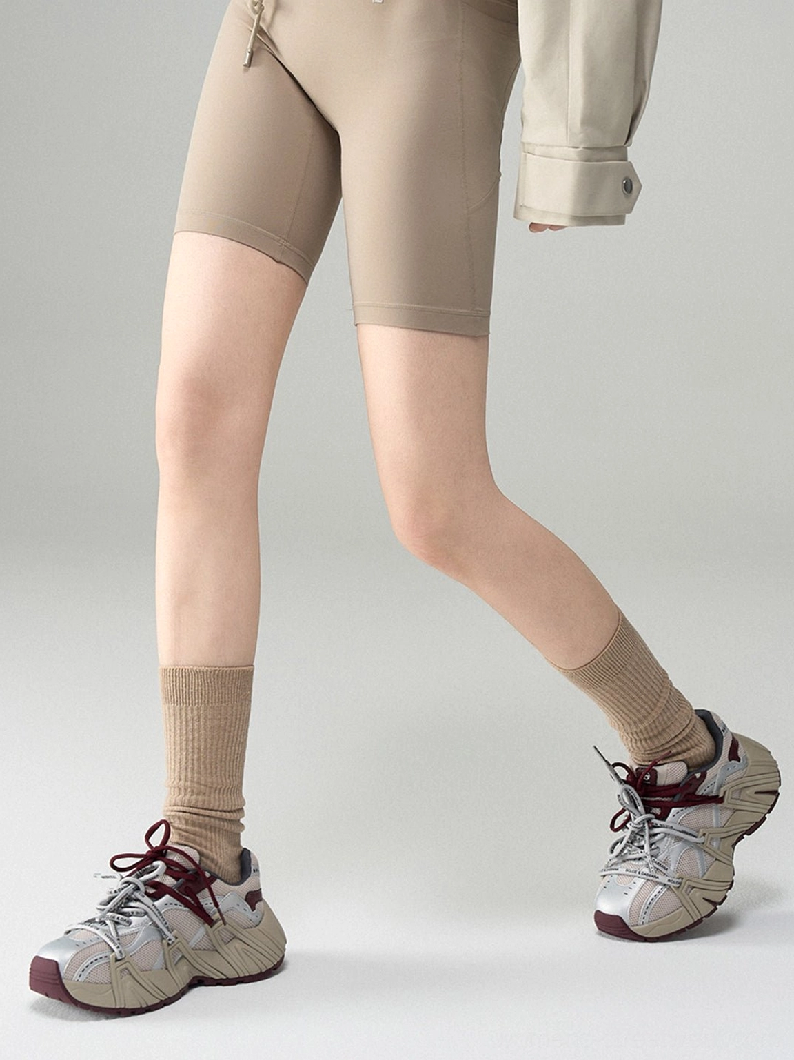 Women's beige mesh cage runner sneakers styled with tan crew socks and biker shorts for a Seoul streetwear outfit