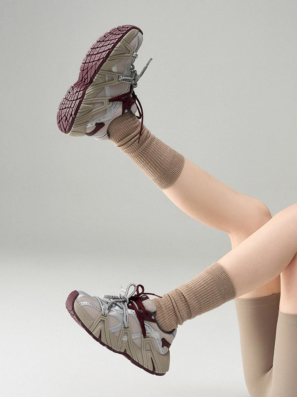 Women's beige technical mesh cage runner sneakers worn with crew socks showing side profile segmented outsole and tread