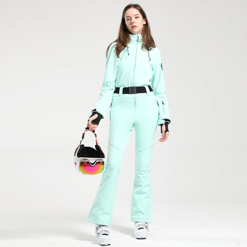Women's mint green one-piece ski jumpsuit with flared legs black waist belt and ski goggles