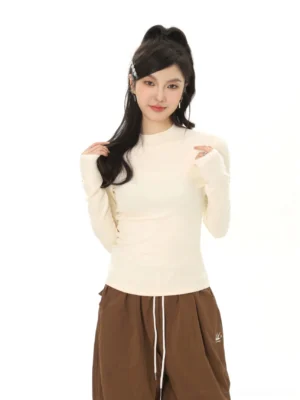 Cream off-white women's mock neck fitted base layer top with fine ribbed knit texture and slim Korean streetwear silhouette shown in a minimalist studio
