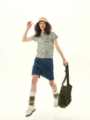 Women’s gray olive camouflage cropped baby tee styled with denim shorts sneakers and crossbody bag full body view