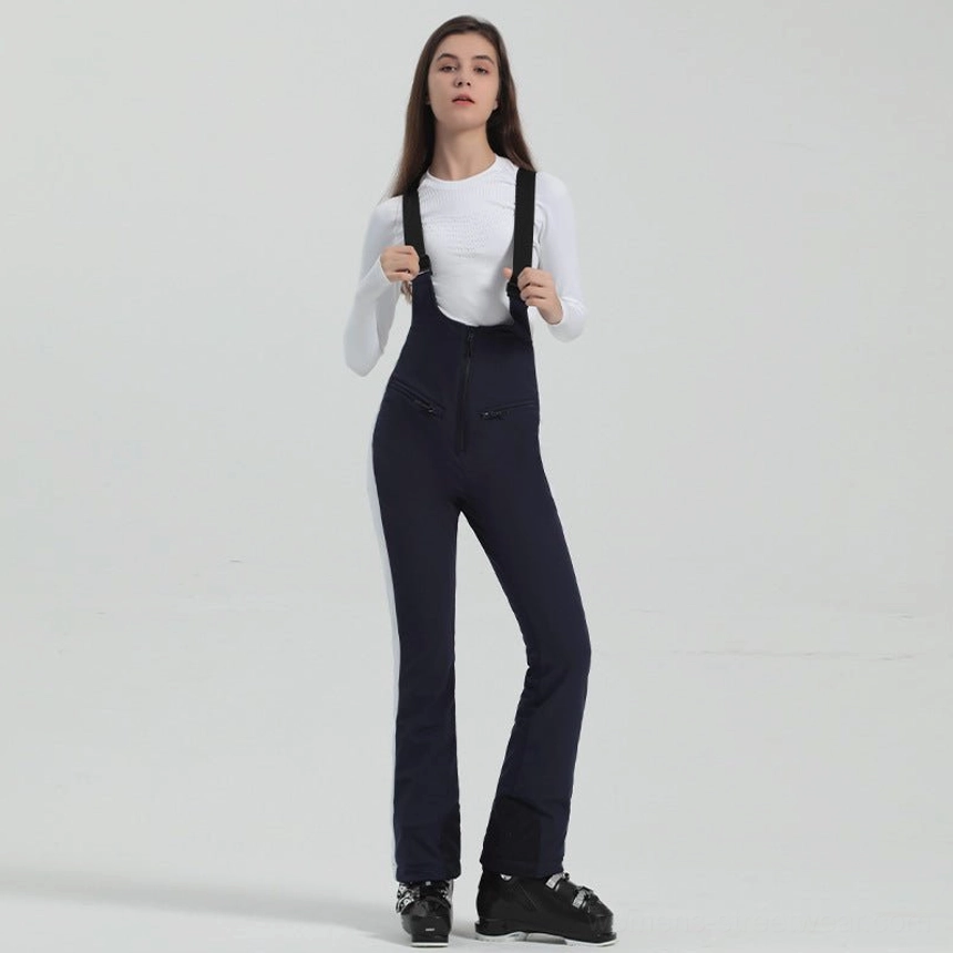 Women's navy blue flared bib ski overalls with white side accents, adjustable black suspenders, front zipper, and ski boots