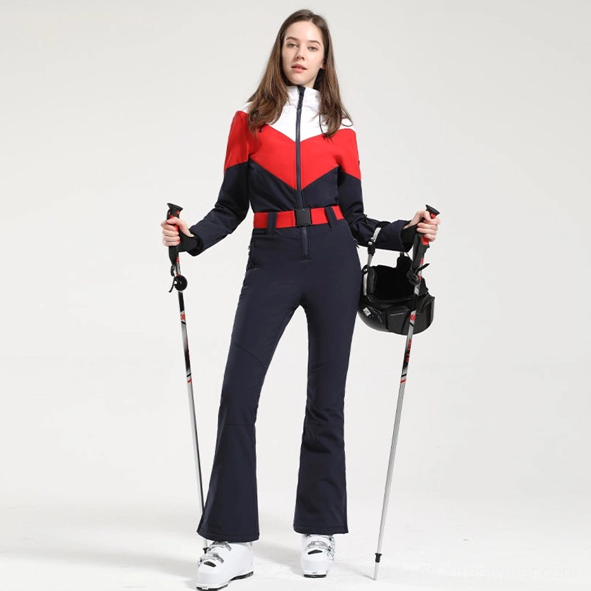 Women's navy red white colorblock one-piece ski suit shown from the front with flared navy pants red belt ski poles and helmet