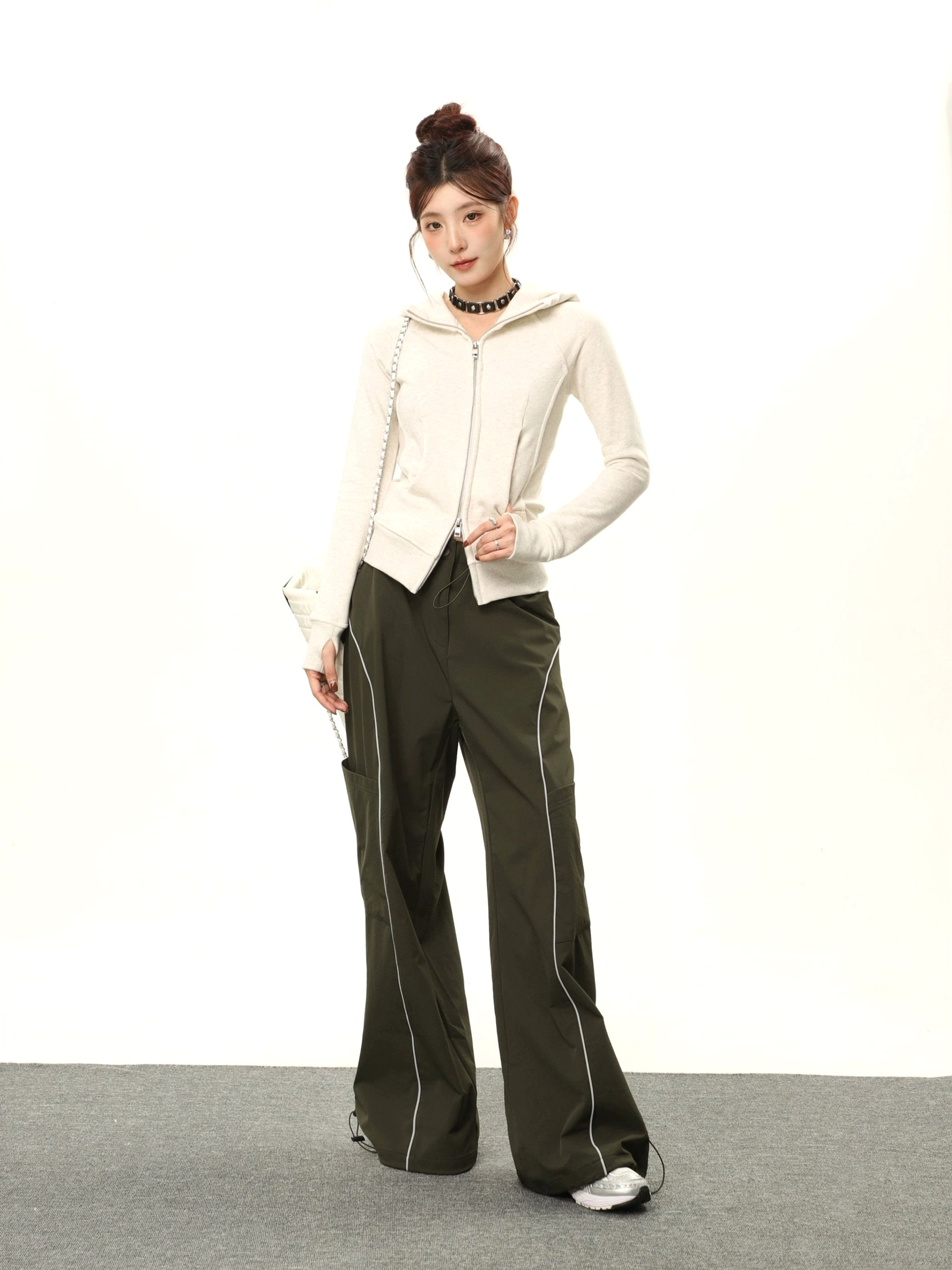 Full-body view of a women's oatmeal gray-beige hooded zip sweatshirt styled with dark green cargo pants in a Korean streetwear outfit