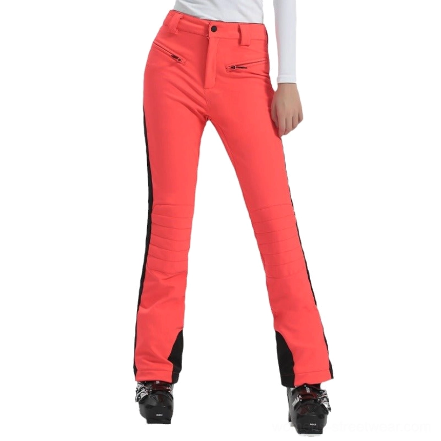 Orange red women's slim fit flared ski pants with black side stripes, zip pockets, bootcut cuffs, and alpine streetwear styling