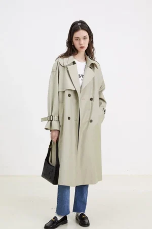 Women's light beige oversized double-breasted belted trench coat styled with jeans and loafers