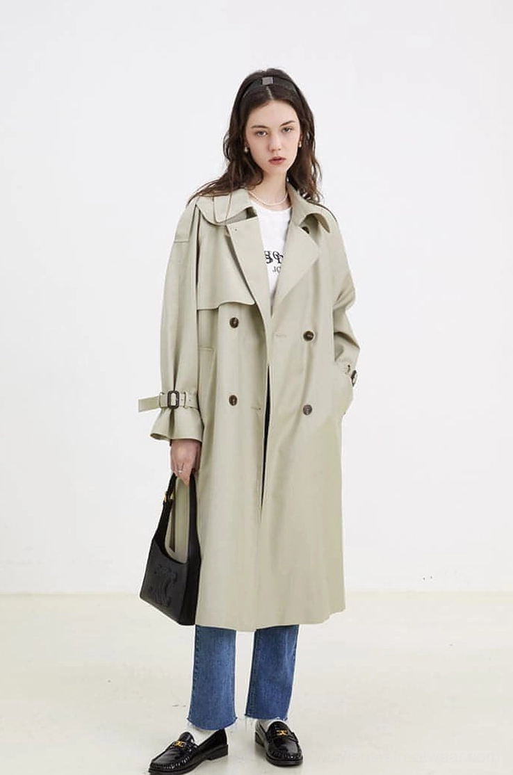 Women's light beige oversized double-breasted belted trench coat styled with jeans and loafers