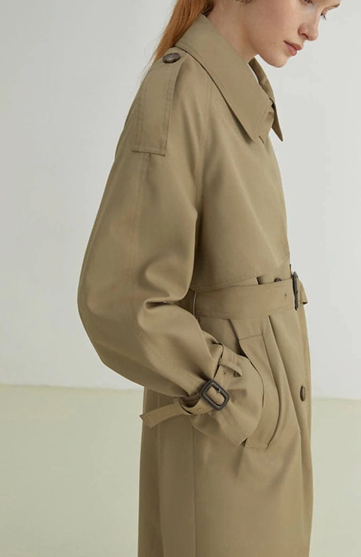 Women's khaki oversized trench coat close-up showing waist belt buckle pocket and shoulder epaulet