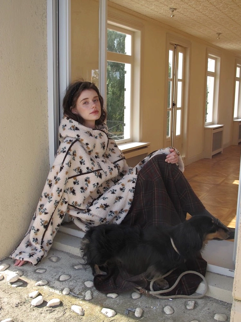 Women's oversized floral print sherpa hooded jacket with black trim styled in an outdoor streetwear setting