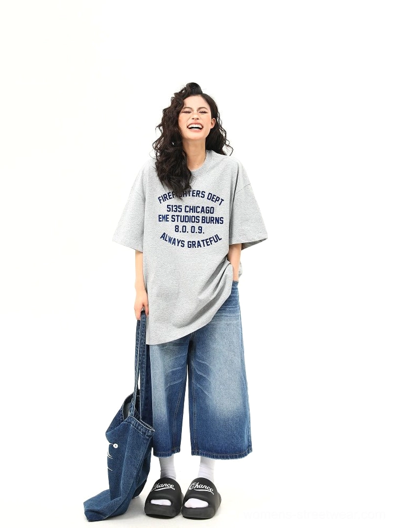 Women wearing oversized heather gray Chicago firefighter lettering graphic tee with wide leg denim jeans front view