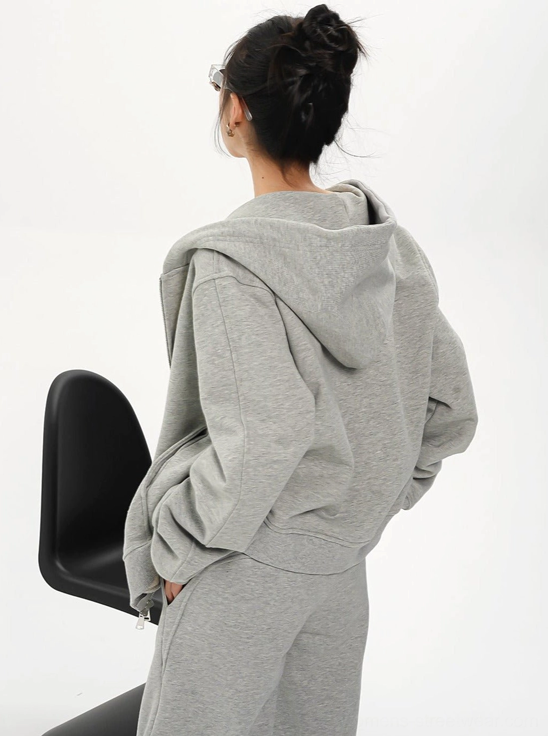 Back three-quarter view of a women's oversized heather gray hoodie jacket with attached hood and relaxed streetwear fit