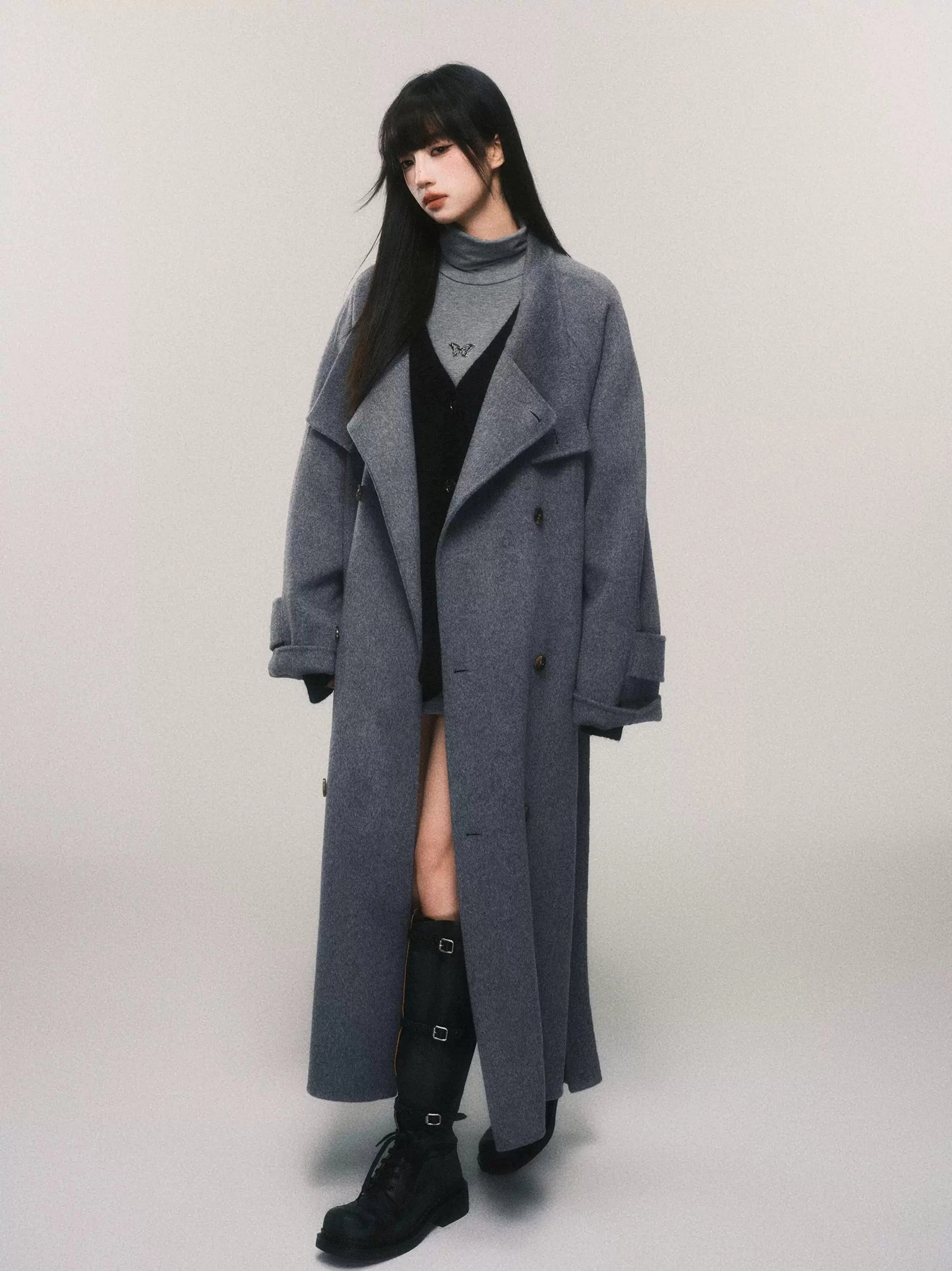 Oversized gray wool maxi trench coat with double-breasted front styled with mini skirt and combat boots