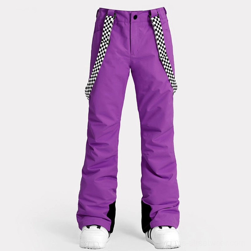 Front studio view of women's purple checkerboard snow pants with flared ski legs, graphic suspenders, black ankle patches, and snow shoes