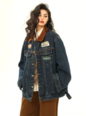 Three-quarter view of women's racing patch denim jacket showing adjustable hem tabs, pockets, and motorsport-inspired streetwear patches