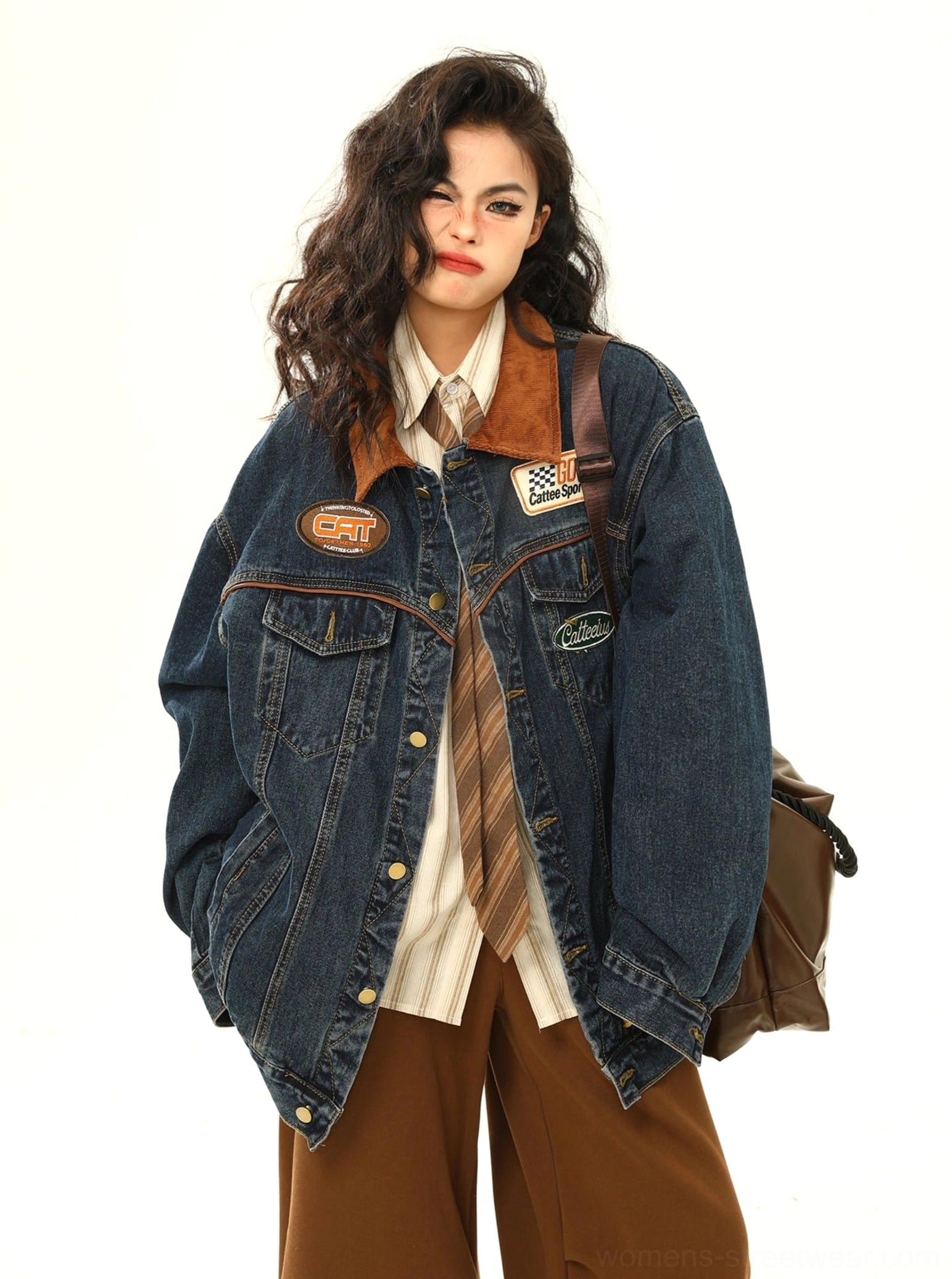 Back three-quarter view of women's racing patch denim jacket styled with a brown leather tote and casual streetwear clothing