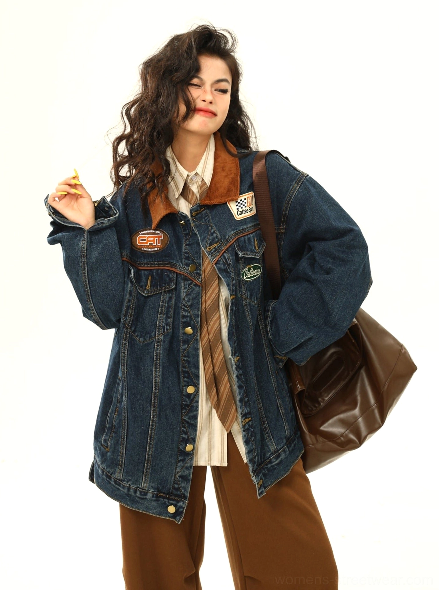 Women's racing patch denim jacket worn in a relaxed everyday outfit with a brown leather tote bag and retro streetwear styling