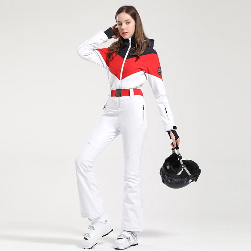 Women's red white black colorblock one-piece ski suit shown from a three-quarter side front view with flared legs adjustable waist belt ski helmet and ski boots