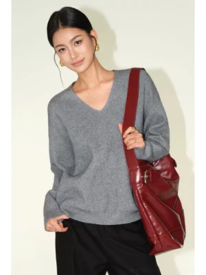 Heather gray women's relaxed V-neck knit sweater with dropped shoulders styled with black trousers and a burgundy leather tote