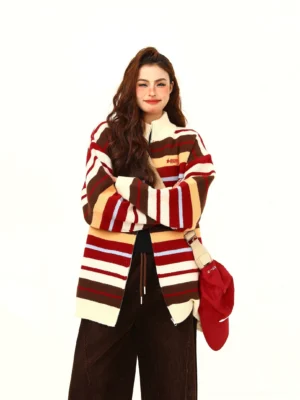 Front view of women's retro striped oversized knit zip-up sweater with stand collar, ribbed trims, chest embroidery, and dark brown trousers
